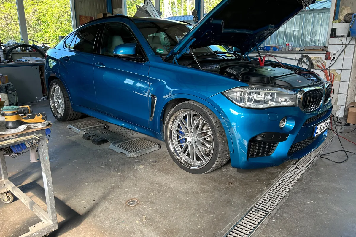 Blauer BMW auf Auffahrrampen in der Werkstatt, Motorhaube geöffnet