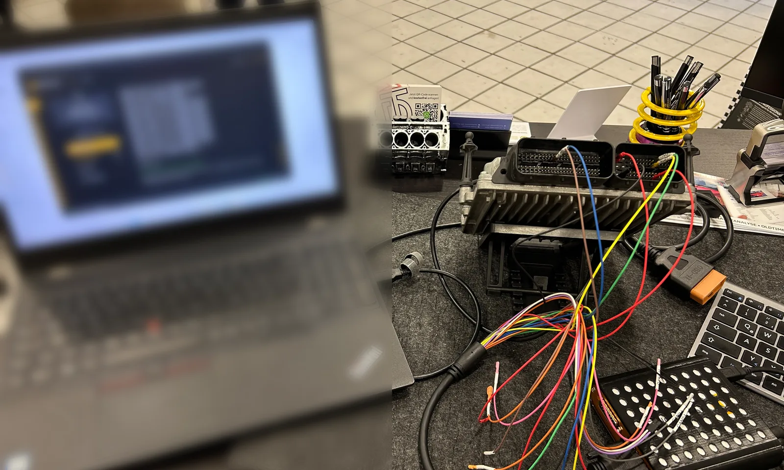 Steuergerät auf dem Arbeitstisch, über einen Kabelbaum mit Laptop und Programmiergerät verbunden